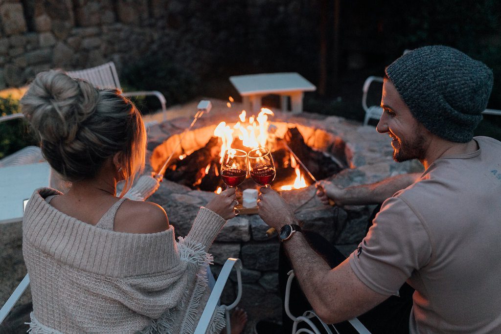 couple toasting their wine glasses sitting by the Farmhouse fire pit
