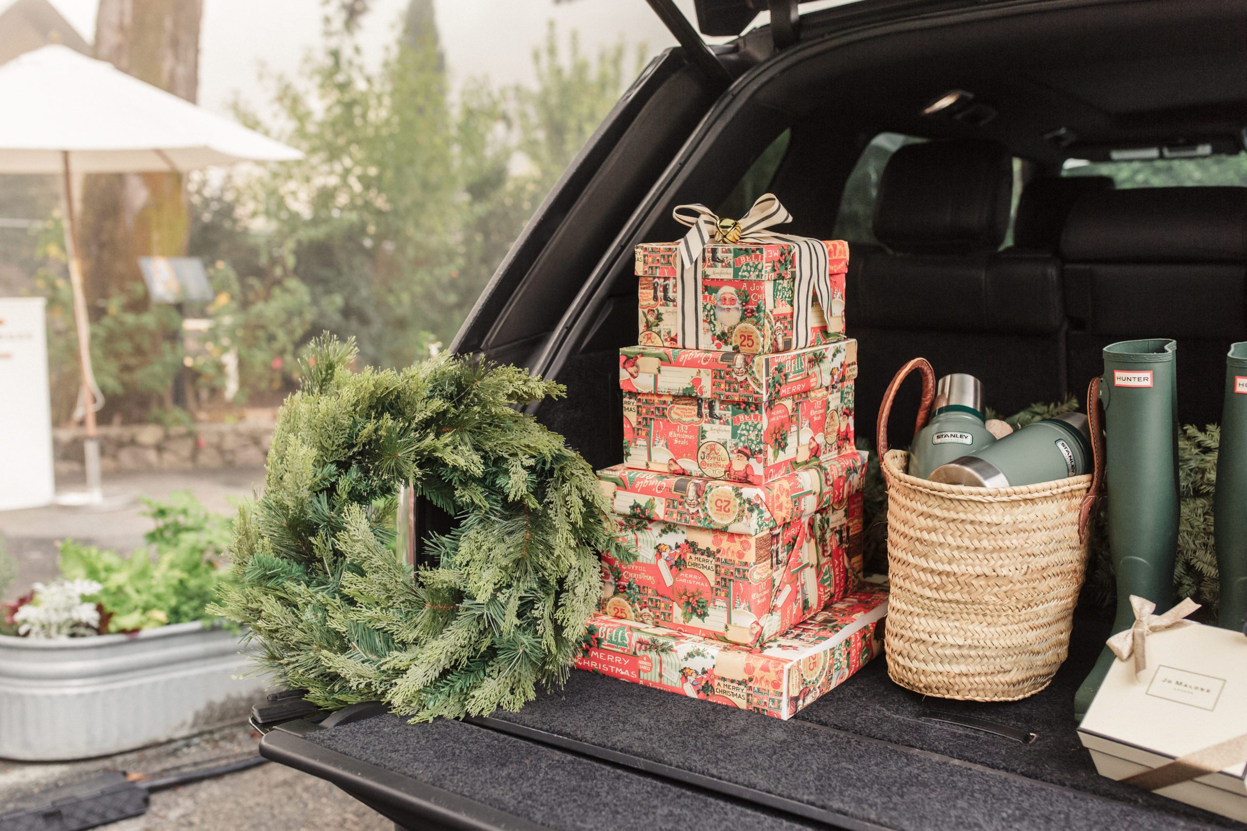 Christmas presents, a wreath, and other goods in the back of a car's trunk