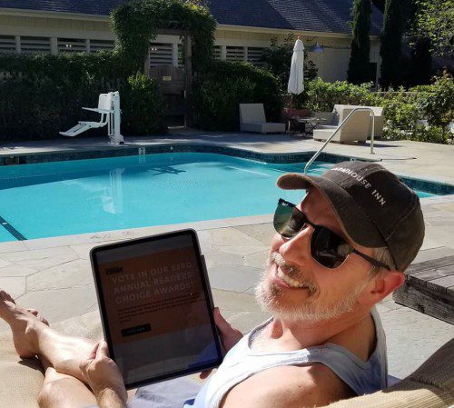 Joe Bartolomei smiling for a photo while sitting poolside with an ipad