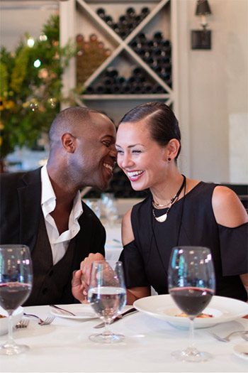 Man and woman sitting at table in restaurant conversing with wine on the table.