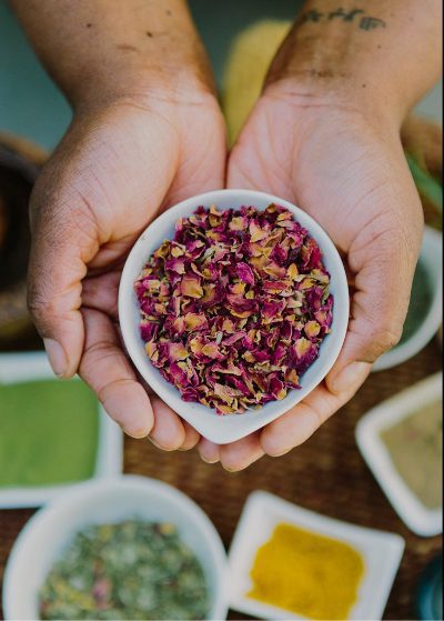 close-up of hands holding a small bowl of grinded-up herbs