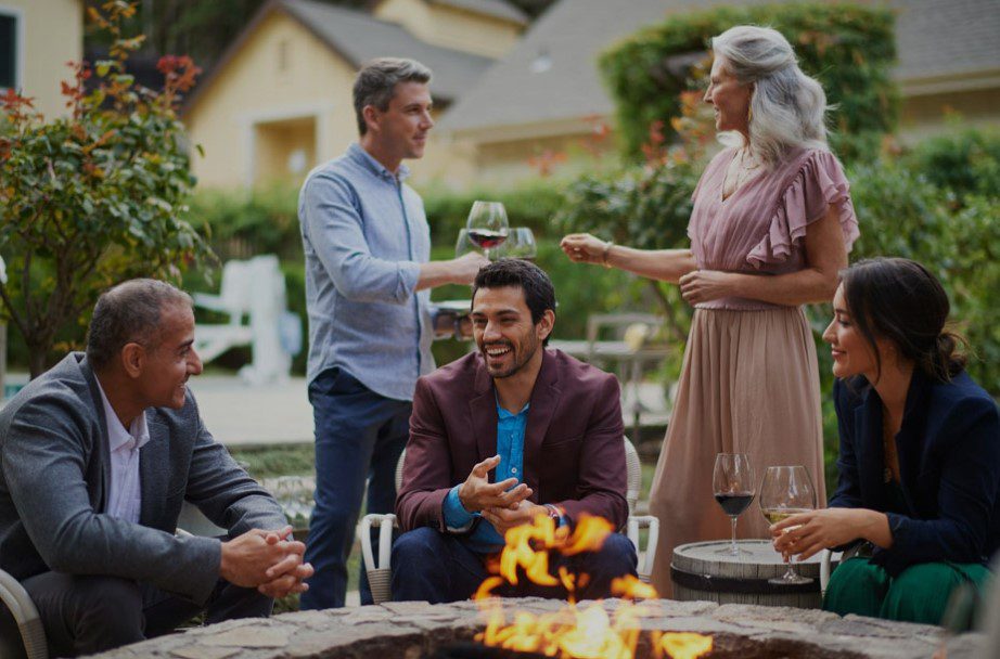 Several guests at the Farmhouse Inn enjoying wine at the fire-pit with fire blazing.