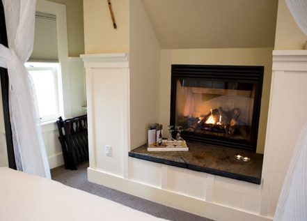 Farmhouse fireplace with lit fire and tray of food on the stone mantle.