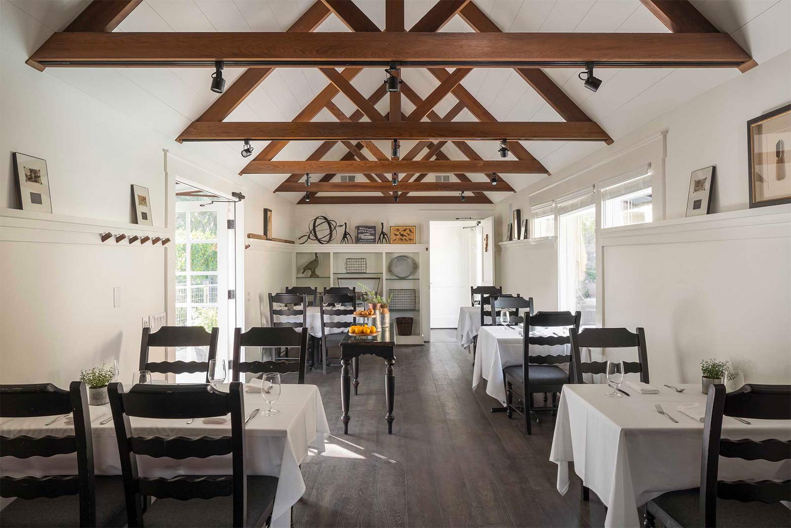 Photo inside the restaurant with white linen tablecloths and napkins, black chairs and elegant table settings.