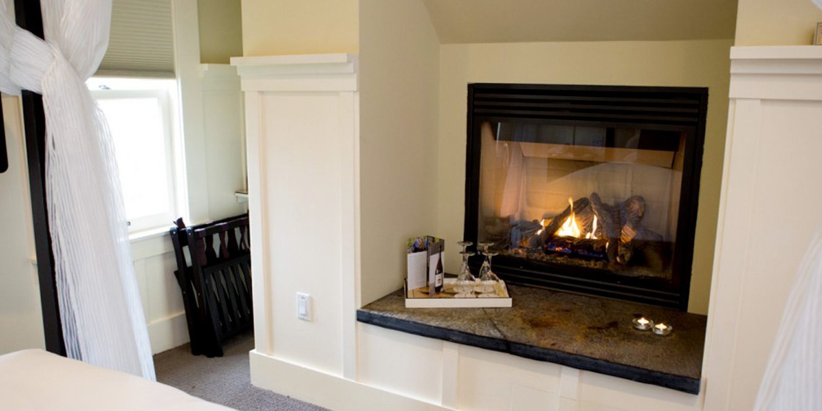 Farmhouse fireplace with lit fire and tray of food on the stone mantle.