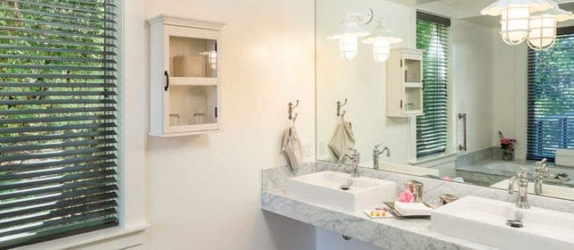 Barn One Bedroom Suite bathroom: large ornate sink with full wall mirror above and hanging cabinet to the left with glasses.