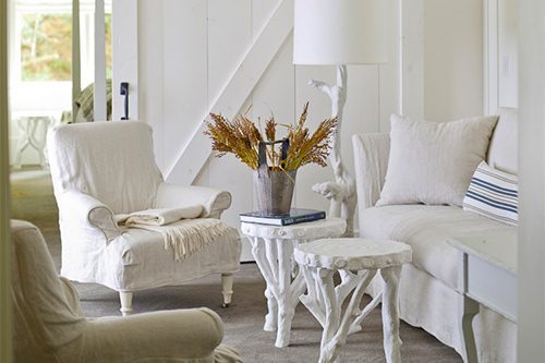 Interior of Barn One Bedroom Suite: White wood partition sliding door in back, white cushioned chair and loveseat with white corner lamp and two small coffee tables.