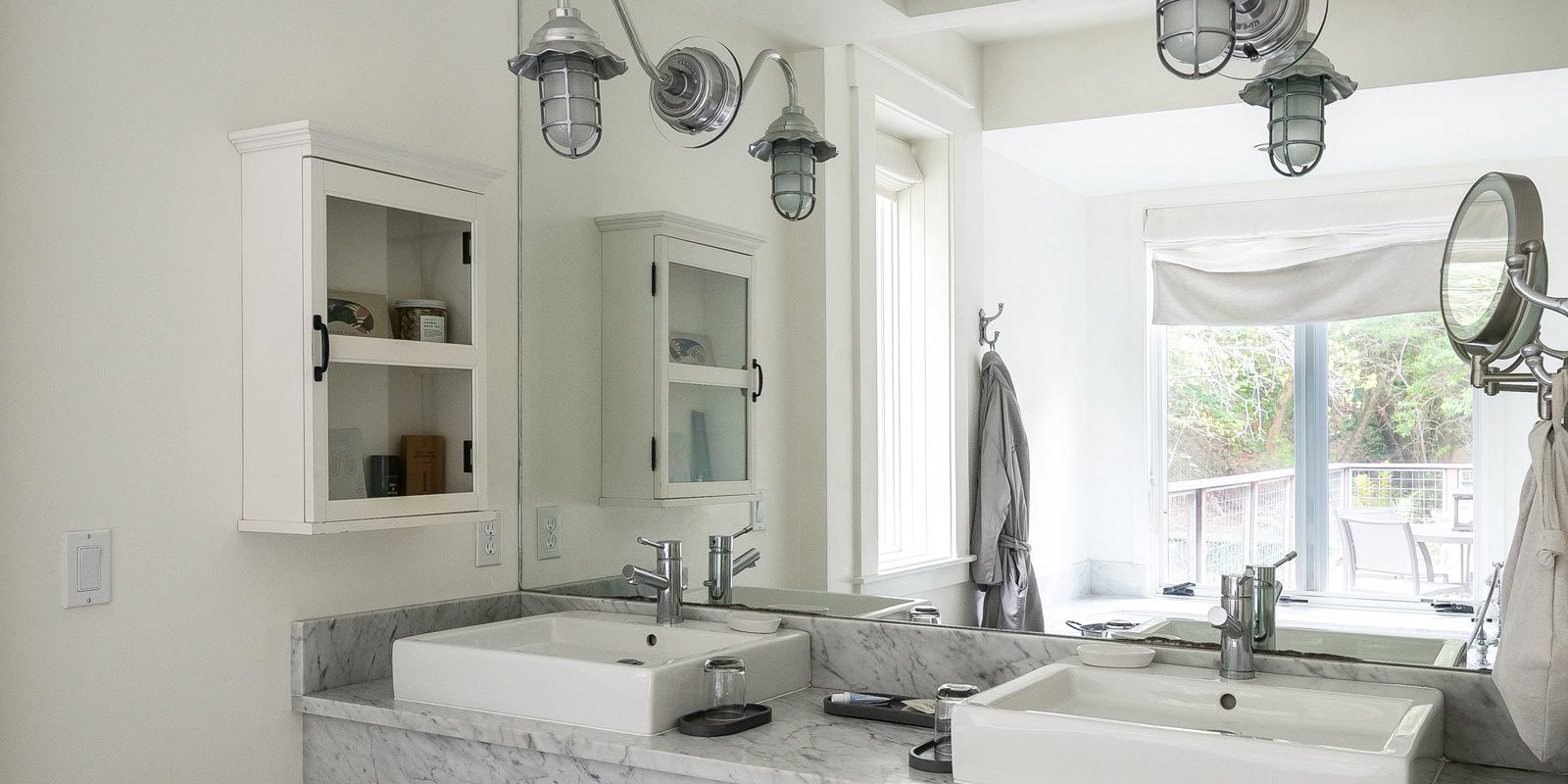 Interior of Barn One Bedroom Suite bathroom. Close-up of side by side sinks on a marble counter with full wall mirror above.