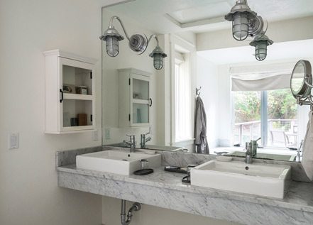 Interior of Barn One Bedroom Suite bathroom. Close-up of side by side sinks on a marble counter with full wall mirror above.