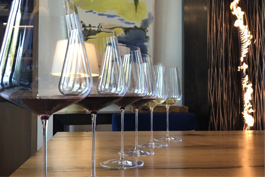 close up shot of a row of 6 wine glasses with a tasting of a red wine