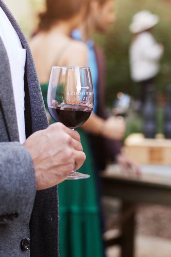 Farmhouse guest, man, holding glass of red wine during Farmhouse wine hour