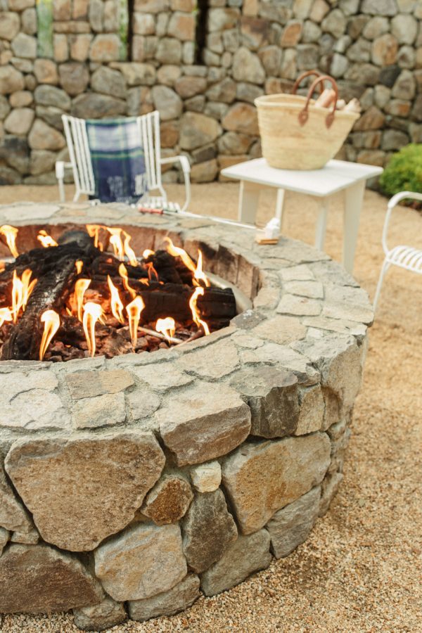 Farmhouse firepit with small fire lit and table, chairs with picnic basket