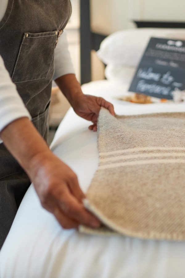 Farmhouse Inn employee making bed and folding sheet