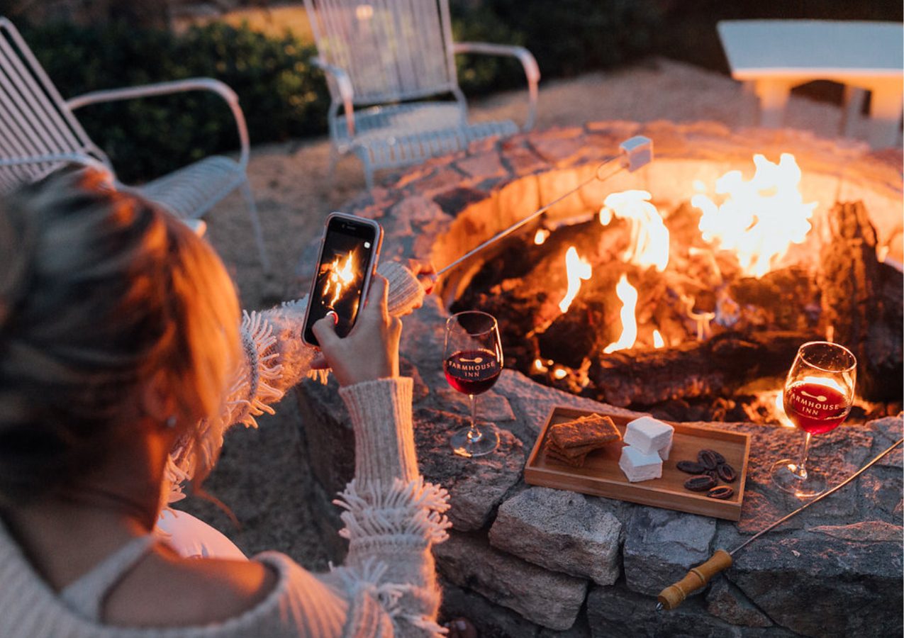 Farmhouse guest taking a picture of the lit firepit and complimentary s'more set up