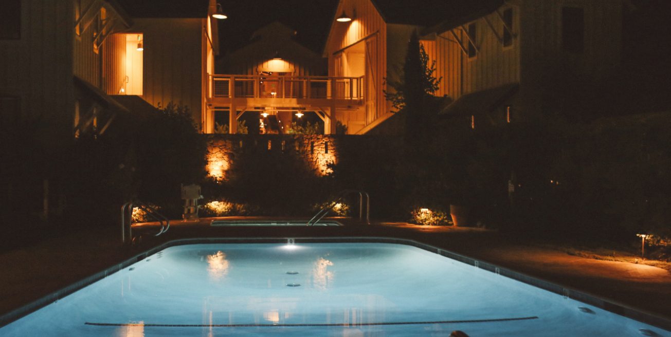 Farmhouse Inn pool at night: warm lights light up the barn rooms and blue pool