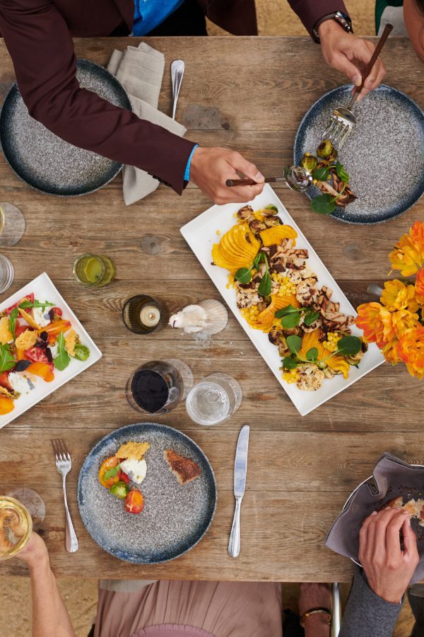 overhead view of wood table with 3 plates of appetizers and several people's place settings