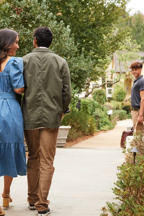 Farmhouse guests walking up the entrance path, being greeted by a bell man.