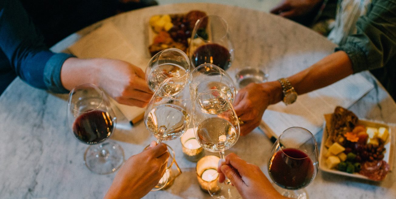 aerial shot of a group of people cheersing with their wine glasses, mix of red and white wine