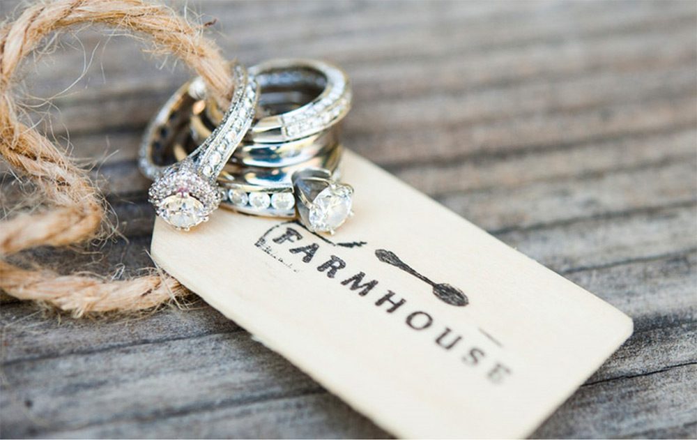 farmhouse tag with twine and engagement rings and wedding bands on wood table