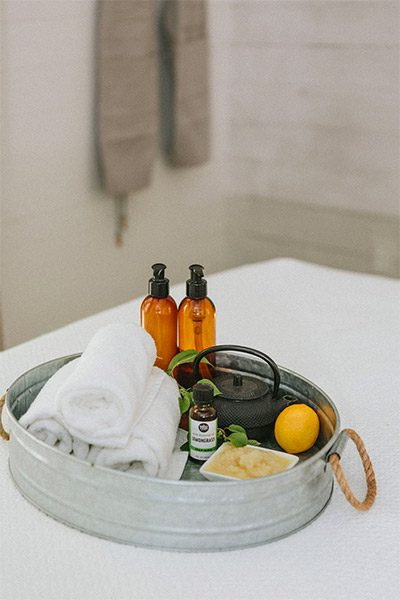 close-up of table with white linen table cloth and metal round tray of spa treatment products.