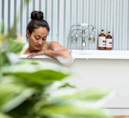 close to floor photo of a woman taking a bath with her head and arm reaching over edge of tub