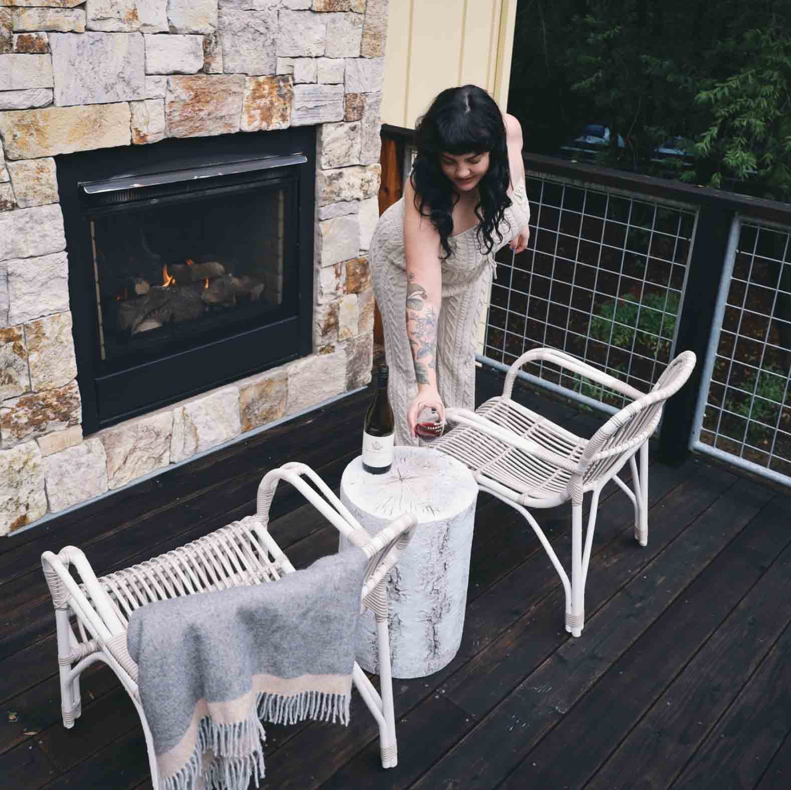 Woman on balcony adjusting chairs around outdoor fireplace