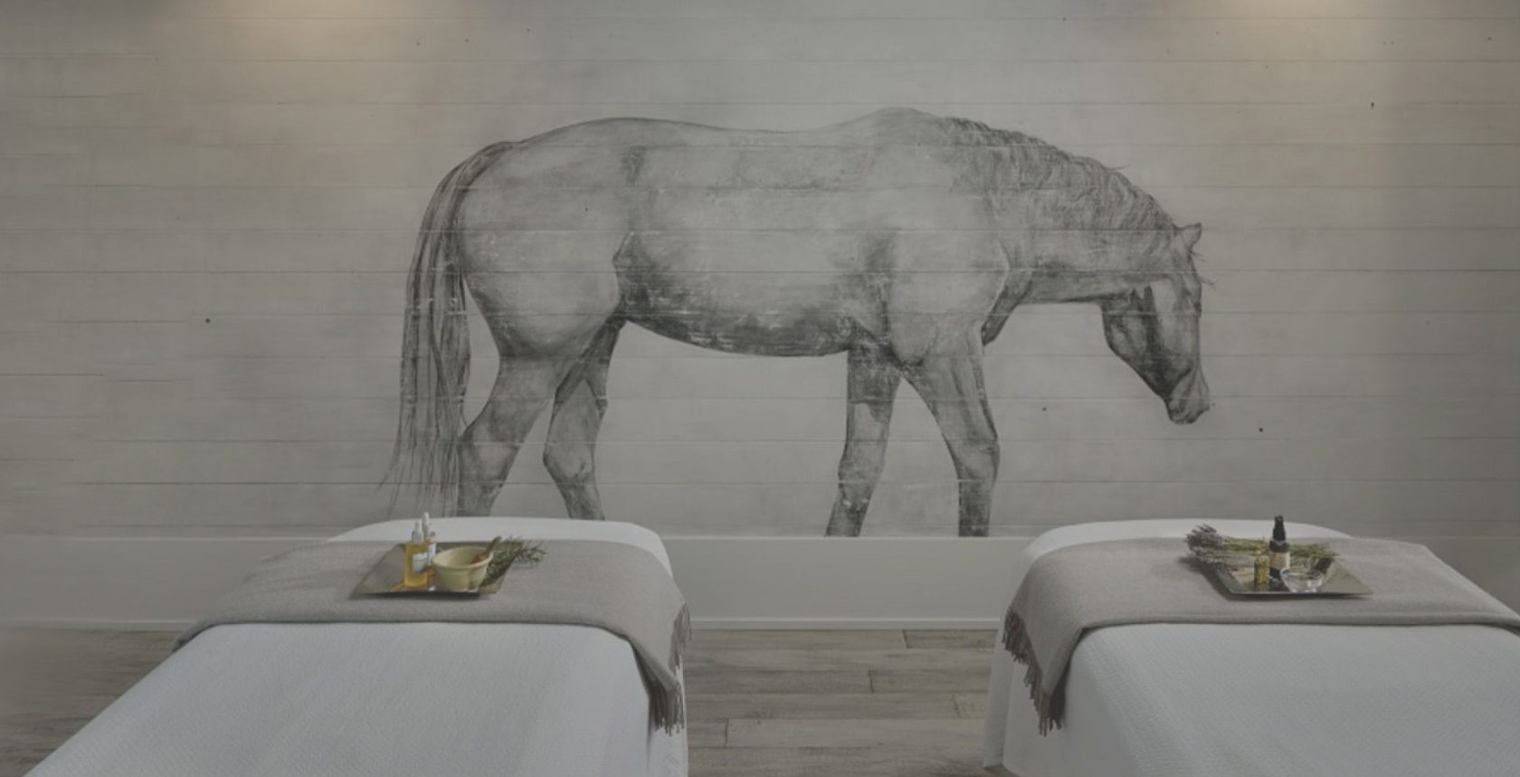 Interior view at the Farmhouse Inn Spa: two massage tables with massage ointments neatly placed and background wall painting of a horse.