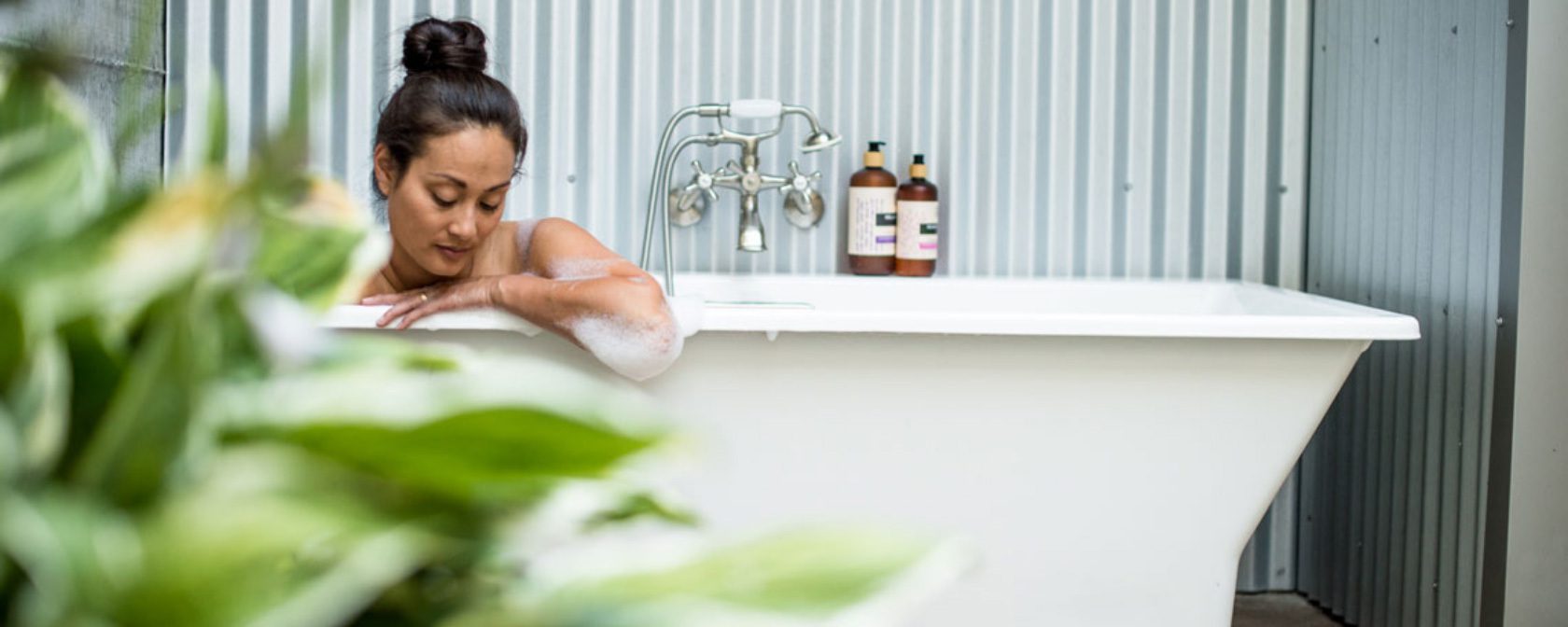 close to floor photo of a woman taking a bath with her head and arm reaching over edge of tub