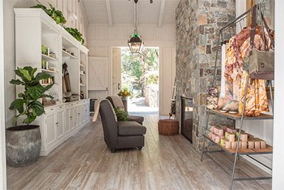 Interior view of Farmhouse Inn Spa: wood floors, large white credenza against wall to the left, cushioned chair in the middle, large stone fireplace to the right