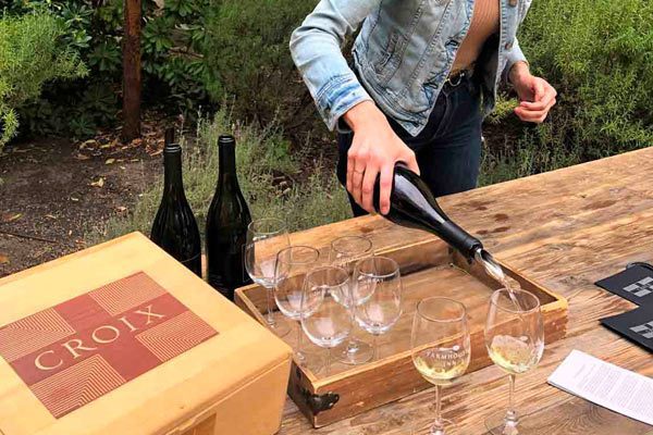 woman behind table pouring tasting glasses