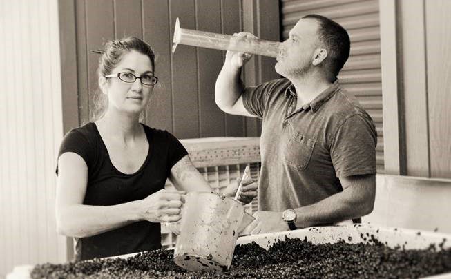 black and white photo of couple smashing grapes to create wine