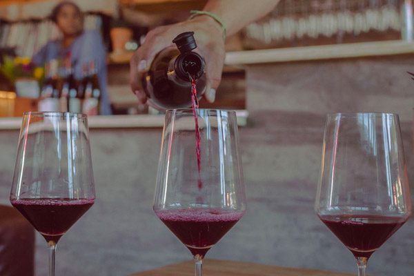 woman pouring three glasses of red wine