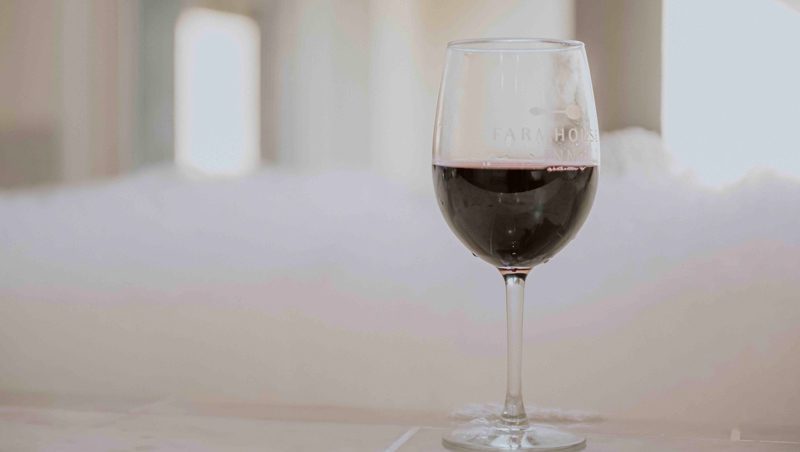 Glass of red wine with Farmhouse Inn logo on the glass