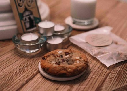 Hotel room table with candles, cookies, milk and a little book titled, 