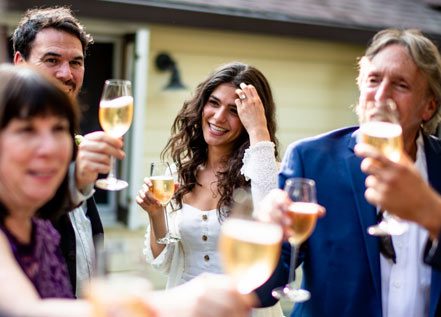 group of people toasting with glasses of white wine