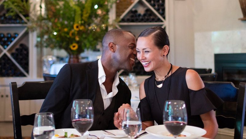 Man and woman sitting at table in restaurant conversing with wine on the table.